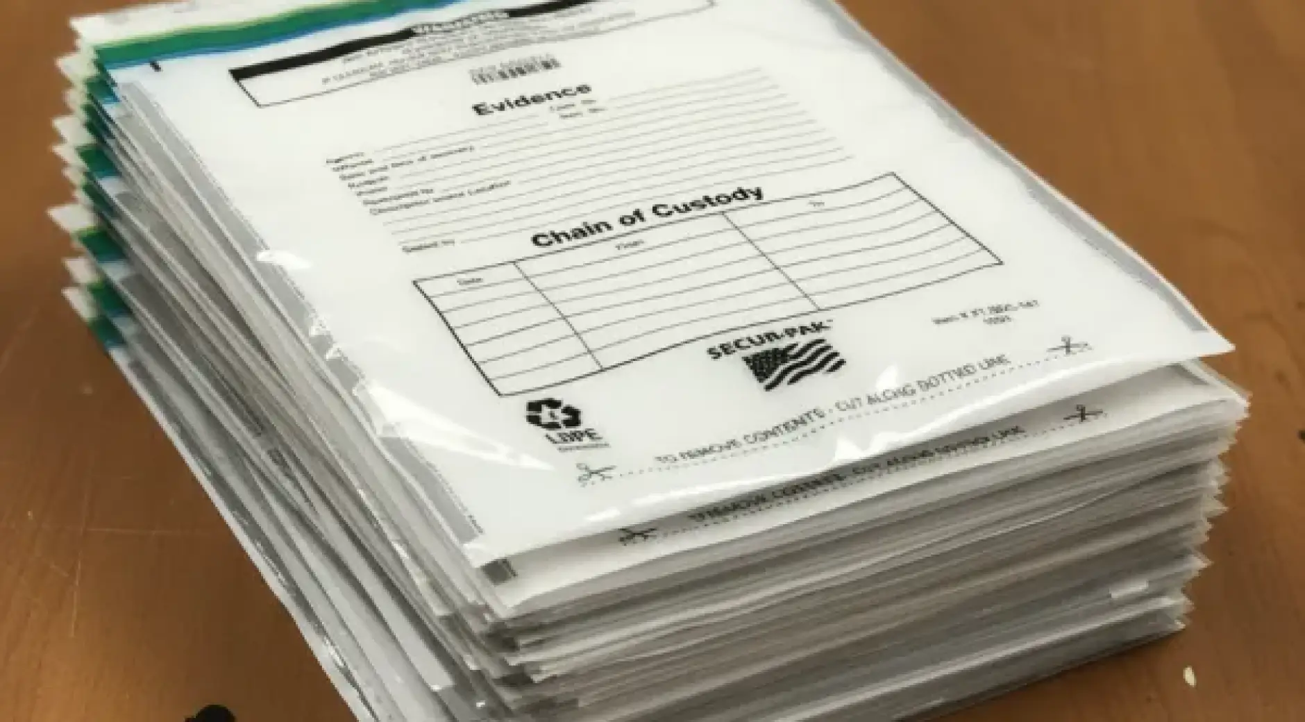 Stacked evidence bags showing multiple layers of SECUR-PAK branded bags with printed documentation fields and tamper-evident seals.